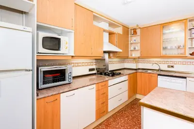 a kitchen with wooden cabinets and white appliances at HomeHolidaysRentals Keyla in Pineda de Mar