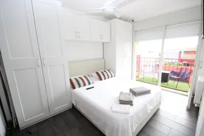 a white bedroom with a bed and a window at casa en Masnou junto a playa y tren in Masnou