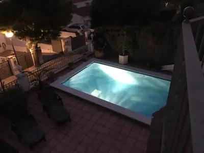 a swimming pool with two chairs next to it at HOUSE WITH AMAZING VIEWS , OVERLOOKING THE FESTIVAL TOWN OF SITGES in Sitges
