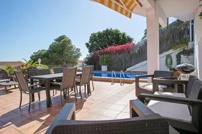 a patio with a table and chairs and a pool at HOUSE WITH AMAZING VIEWS , OVERLOOKING THE FESTIVAL TOWN OF SITGES in Sitges