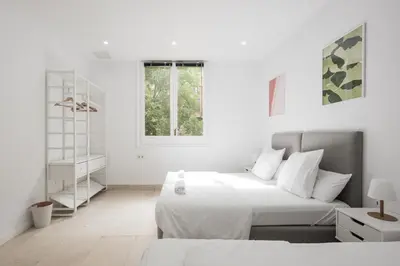 a white bedroom with two beds and a window at No Limit Barcelona Central in Barcelona