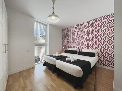 a bedroom with two beds and a red and white patterned wall at Stay U-nique Apartments Pellaires in Barcelona