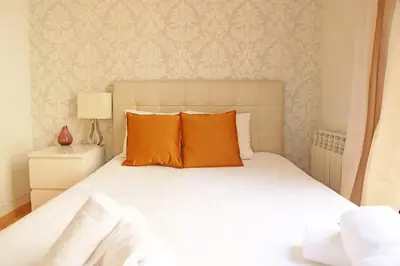 a bedroom with a white bed with orange pillows at Bcn-rentals apartments in the Old town in Barcelona