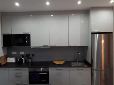 a kitchen with white cabinets and a stainless steel refrigerator at Beautiful Apartment on Las Ramblas with Port views in Barcelona