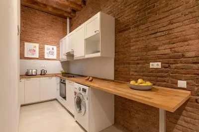 a kitchen with white cabinets and a brick wall at Aspasios Gracia Apartments in Barcelona