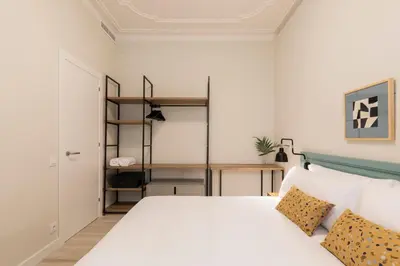 a bedroom with a white bed and a book shelf at Aspasios Gracia Apartments in Barcelona