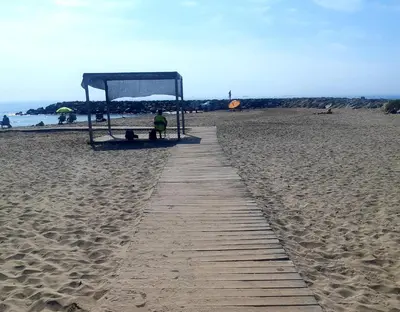 a boardwalk leading to a shelter on a beach at APARTAMENTO EN SEGUNDA LINEA DE MAR, WIFI & A.C in Cubelles
