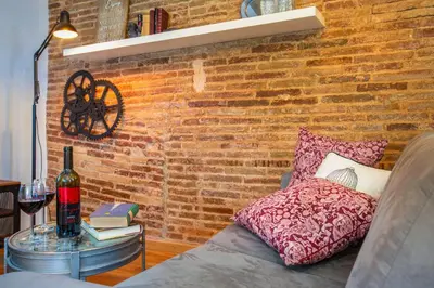 a brick wall with a pillow and a table with a bottle of wine at Stay U-nique Apartments Ramón y Cajal in Barcelona