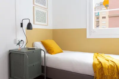 a bedroom with a bed with a yellow pillow and a window at Casa Cosi - Sant Gervasi 1 in Barcelona