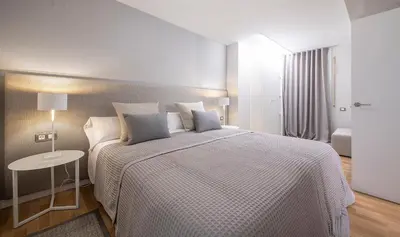 a white bedroom with a large bed and a table at Poble Nou II You Stylish Apartments in Barcelona