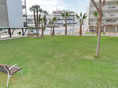 a park with a bench and palm trees and a building at Sol & Relax en centro, Sitges. in Sitges