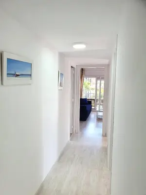 an empty hallway with white walls and a blue couch at Sol & Relax en centro, Sitges. in Sitges