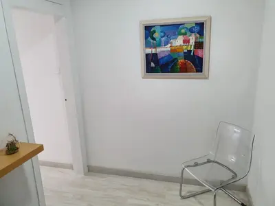 a chair in a room with a painting on the wall at Sol & Relax en centro, Sitges. in Sitges