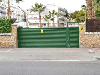 a green garage door on the side of a street at Sol & Relax en centro, Sitges. in Sitges