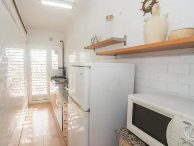 a kitchen with a white refrigerator and a microwave at Sol & Relax en centro, Sitges. in Sitges