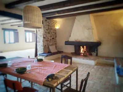 a dining room with a table and a fireplace at Masia Mediterranian Country House Ca l'Isidre Torrent in Sant Cebrià de Vallalta