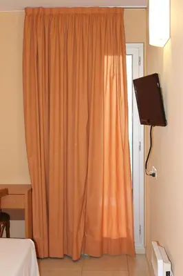 an orange curtain in a room with a television at Hostal Cal Siles in El Prat de Llobregat