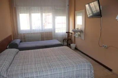 a hotel room with two beds and a television at Hostal Cal Siles in El Prat de Llobregat