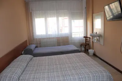 a bedroom with two beds and a window at Hostal Cal Siles in El Prat de Llobregat