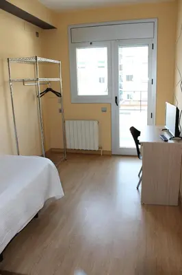 a bedroom with a bed and a desk with a computer at Hostal Cal Siles in El Prat de Llobregat