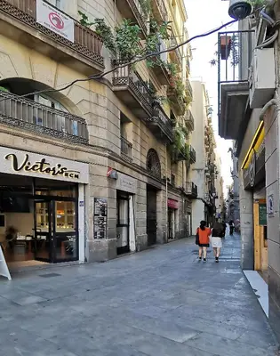 two people walking down a street next to a building at ClassBedroom Gothic Ramblas Apartments in Barcelona