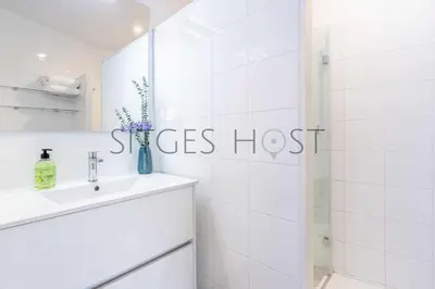 a white bathroom with a sink and a shower at Magnificas vistas al mar in Sitges