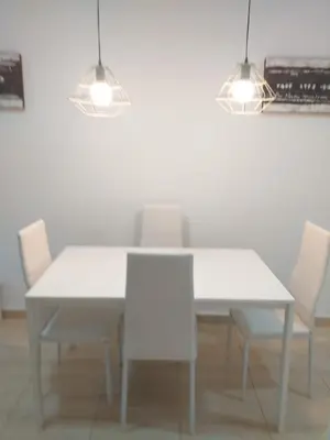 a white dining room table with white chairs and lights at Mejor Apartamento en Plaza España con Parking Gratuito in Barcelona