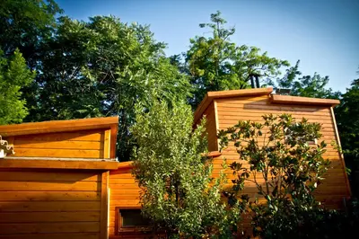 a wooden building with a gate and a bush at Refugio cálido,estilo nórdico el Bosquet in Sant Cugat del Vallès