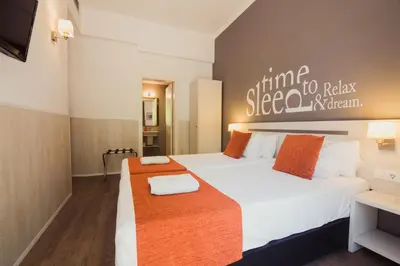 a bedroom with a bed with white sheets and orange pillows at Hostal Live Barcelona in Barcelona