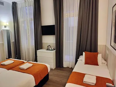 two beds in a hotel room with curtains at Hostal Live Barcelona in Barcelona
