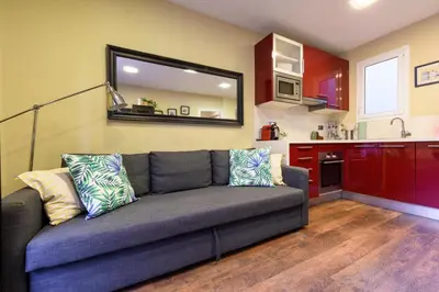a living room with a couch and a kitchen at RamblasRentals Cozy Renovated 2BR with Balcony Lift 20M Rambla - Parking - Wifi in Barcelona