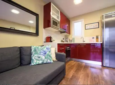 a living room with a couch and a kitchen at RamblasRentals Cozy Renovated 2BR with Balcony Lift 20M Rambla - Parking - Wifi in Barcelona
