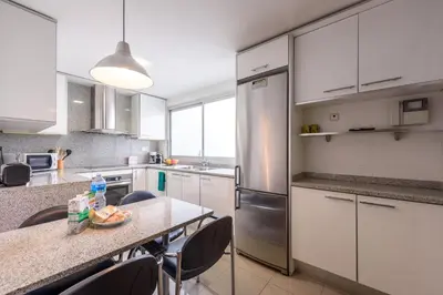 a kitchen with a table with chairs and a refrigerator at RamblasRentals Stylish Bright 3BR New Catalan Flat 10m Ramblas - Parking - Wifi in Barcelona