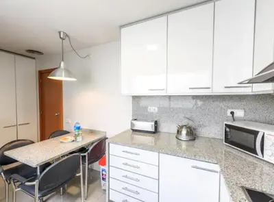a kitchen with white cabinets and a table with chairs at RamblasRentals Stylish Bright 3BR New Catalan Flat 10m Ramblas - Parking - Wifi in Barcelona