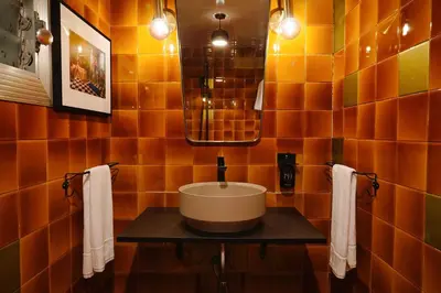 an orange tiled bathroom with a sink and a mirror at Isabella's House in Barcelona
