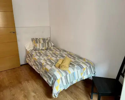 a small bedroom with a bed and a chair at Amplio Apartamento cerca de FIRA y del Centro in Hospitalet de Llobregat