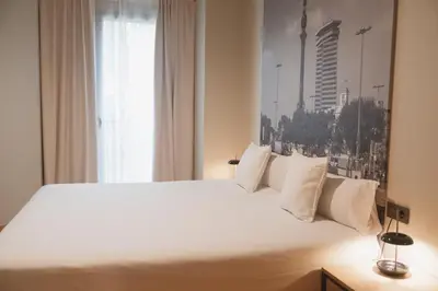a bedroom with a large white bed with a window at Apartments Hotel Sant Pau in Barcelona