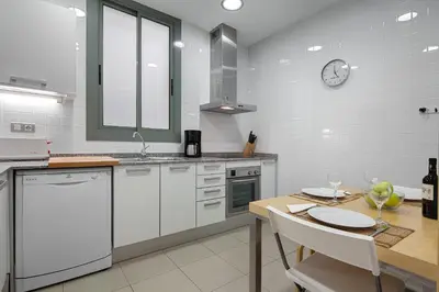 a kitchen with a table and a clock on the wall at Habitat Apartments Alibei in Barcelona