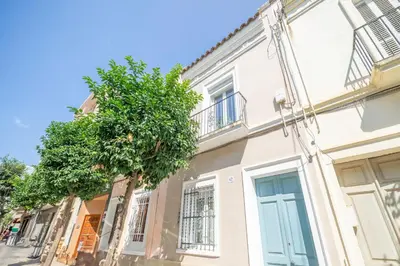 a white building with a tree in front of it at HomeHolidaysRentals Arlene in Calella