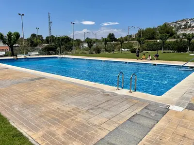 a swimming pool with blue water in a park at La Marina SeaView Penthouse in Sitges
