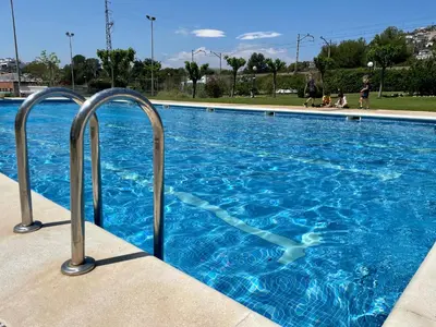 a swimming pool with blue water and metal rails at La Marina SeaView Penthouse in Sitges