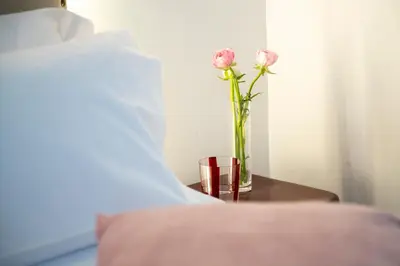 two pink roses in a vase on a table next to a bed at Hotel Casa Trafalgar Barcelona in Barcelona