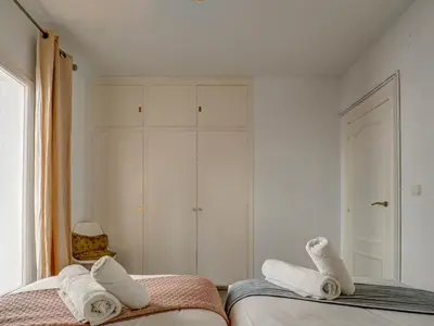 a white bedroom with two beds and towels at The Lilium Apartment by Hello Homes Sitges in Sitges