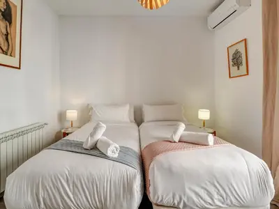 two beds in a room with white sheets and towels at The Lilium Apartment by Hello Homes Sitges in Sitges