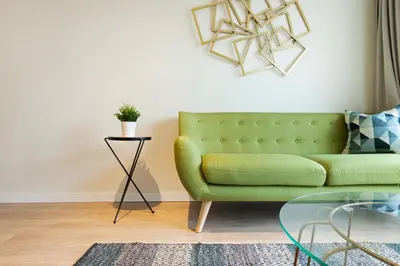 a living room with a green couch and a glass table at Tendency Apartments Forum 4 in Sant Adria de Besos