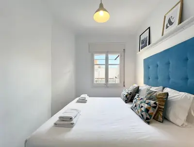 a white bedroom with a large bed with a blue headboard at Stay U-nique Apartments Legalitat in Barcelona