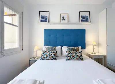 a bedroom with a large bed with a blue headboard at Stay U-nique Apartments Legalitat in Barcelona