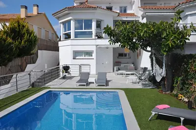 a villa with a swimming pool in front of a house at Miramar Sitges in Sitges