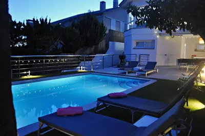 a swimming pool with two loungers next to a house at Miramar Sitges in Sitges