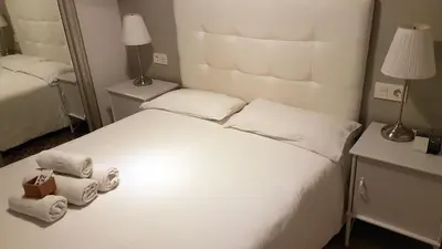 a bedroom with a white bed with two rolled towels at Pensió Cerdanya in Barcelona